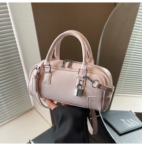 Detail of light pink mini Boston bag featuring smooth leather texture and metal padlock
