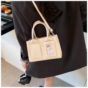 Detail of minimalist off-white bucket bag with transparent card slot and cross-body strap