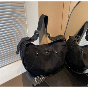 Detail of black denim crossbody bag with adjustable wide strap and dual front zippers