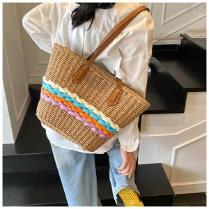Détail de rayures colorées tissées sur un sac en paille avec poignées en cuir marron