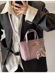 Lavender faux leather bucket bag with doll charm and pearl strap shown by a model