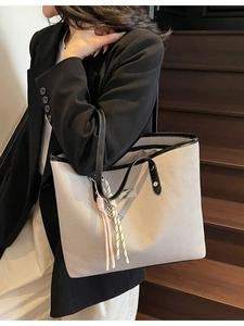 Minimalist woven tote bag in beige with black leather trim and pink tassel charm