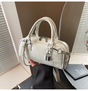 Detailed close-up of white leather bucket bag with silver lock and detachable strap