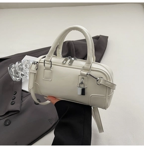Close-up of a white leather Boston bag featuring silver hardware and a side padlock detail