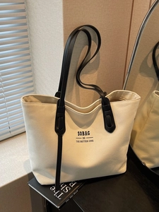 Minimalist cream canvas tote bag with black leather straps and slogan print