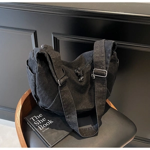 Macro detail of washed black denim hobo bag with silver metal buckle and wide strap