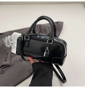 Detail of black glossy leather Boston bag with silver hardware and embossed side patterns