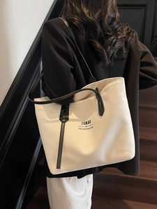Off-white canvas tote bag with black leather handles and SOBAG typography on front