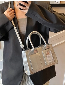 Chic metallic silver bucket bag with card slot, worn crossbody over a black suit