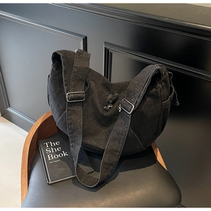 Detail of vintage black denim hobo bag featuring thick washed canvas and silver buckles