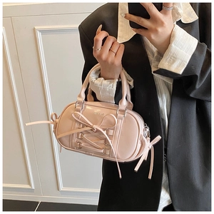 Detailed shot of pink glossy Boston bag featuring decorative bows and lace-up details