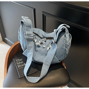 Macro shot of light blue denim fabric texture and crescent shoulder bag zipper details