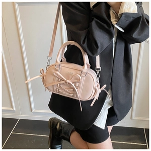 Close-up of pink Boston bag featuring decorative cross-lacing and sweet bow details