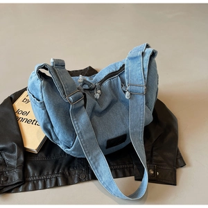 Detail of light blue denim crossbody bag featuring metal buckle and frayed zipper edge