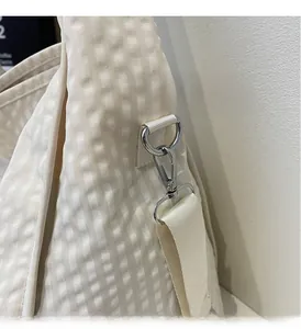 Close-up of cream tote bag featuring silver hardware and pleated ripple texture