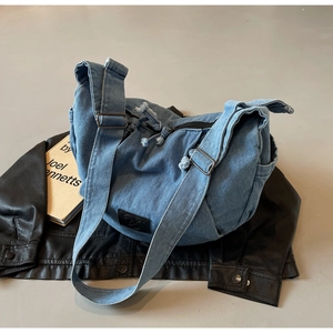 Detail shot of blue denim crossbody bag with adjustable strap and logo patch