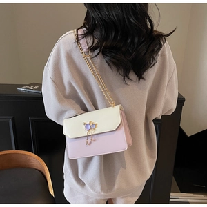Détail du sac bandoulière contrasté avec fermoir oreilles de chat et pompon gemme