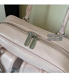 Close-up of smooth silver dual-zipper closure on pink faux leather boston bag