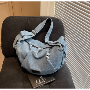 Close-up of light blue denim tote bag with frayed edges on a corduroy chair