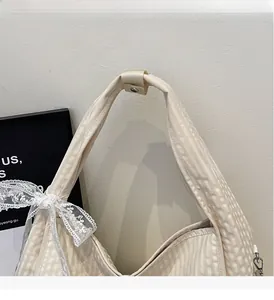 Detail of beige striped canvas tote bag with white lace bow and reinforced handles