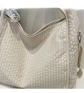 Detail of cream plaid tote bag featuring white lace trim and detachable metal hooks