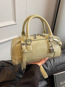 Olive green faux leather Boston bag with silver hardware shown in a hand-held display