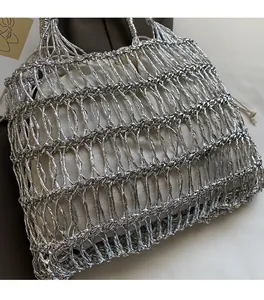 Detailansicht der silbernen Strickhandtasche mit Metallic-Gewebe und weißem Kordelzugbeutel