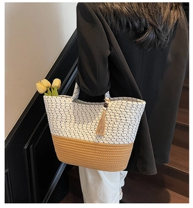 Detail of color-block woven tote bag with fringe tassel and natural straw texture