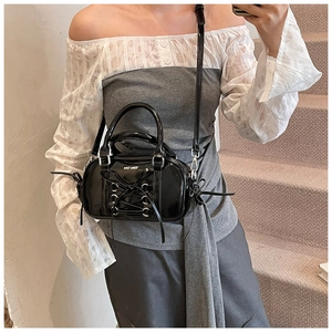 Detail of black patent leather boston bag with corset lace-up design and silver eyelets