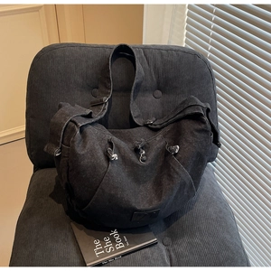 Close-up of black denim crossbody crescent bag with wide strap and drawstring detail