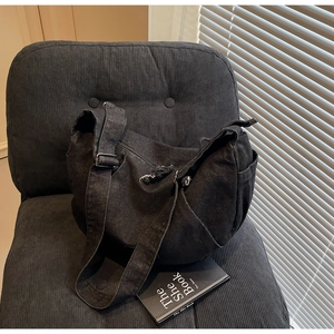 Macro shot of black denim crescent bag with adjustable strap on a velvet chair