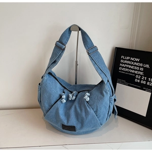 Detailed shot of the light blue denim bag with frayed edges and adjustable strap