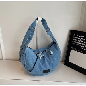 Detail of blue denim hobo bag showing adjustable strap and leather logo patch