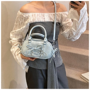 Mirror selfie showing a light blue bow handbag with top handle and adjustable shoulder strap