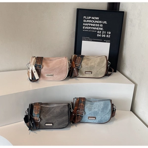 Detail of colorful shoulder bags with bohemian style straps on white display stand