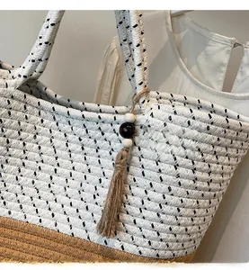 Detailed shot of two-tone woven tote bag with a decorative beaded tassel and straw texture