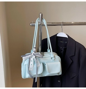 Close-up of light blue patent leather bag with bow detail and front pockets