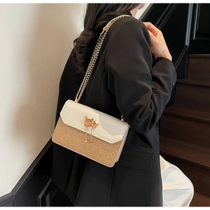 Détail de l'élégante boucle chat en métal avec pompon sur un sac bandoulière scintillant