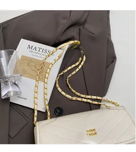 Detail of off-white quilted chain bag with gold logo on dark brown blazer background