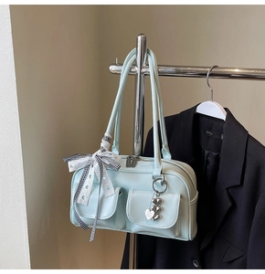 Close-up of light blue leather handbag featuring dual front pockets and heart charm