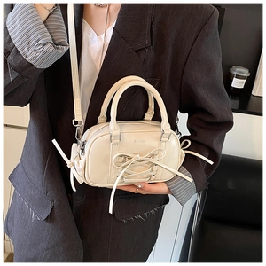 Detail of cream ballet-style Boston bag with bow tie ribbon and crossbody strap