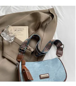 Detail of light blue denim pillow bag featuring ethnic style strap and leather tassels