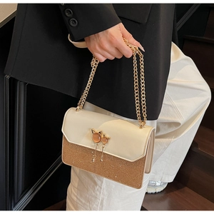 Détail du sac bandoulière avec fermoir chat doré, glands et texture pailletée chic