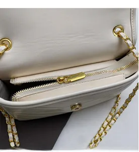 Detail view of smooth golden zipper and chain strap on white quilted leather bag