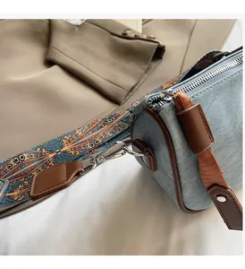 Detailed close-up of blue denim pillow bag showing silver hardware and ethnic strap