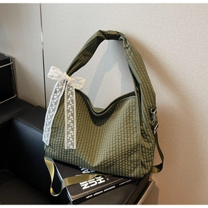 Detail of olive green checkered canvas tote bag featuring a white lace bow and silver hardware