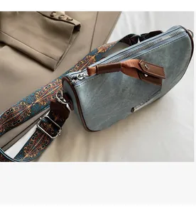 Detail of smooth metal zipper and ethnic pattern strap on light blue denim pillow bag