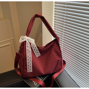 Macro detail of red checkered tote bag featuring a white lace bow and adjustable strap