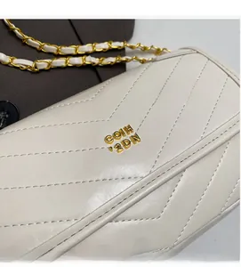 Detailed view of the V-shaped quilted cream leather surface and gold metal logo