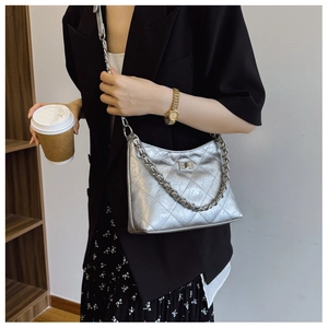 Detailansicht der silbernen Stepptasche mit Kettenverzierung auf einem schwarzen Blazer